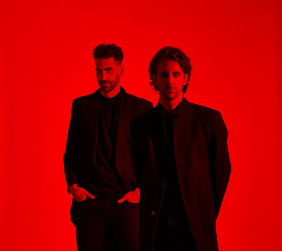 Meet The Listros, a compelling musical duo captured in a striking red-toned portrait. Dressed in black and gazing seriously into the lens, their aesthetic speaks to intensity and artistic depth—perfect for editorial features and music platforms.